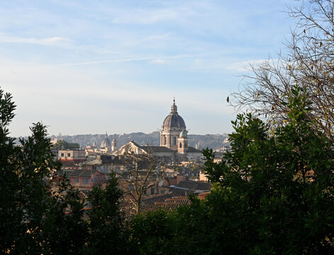 Elevated view across the rooftops of Rome, Italy, featuring the domes of historic churches illuminated by warm evening light. The timeless skyline showcases the Eternal City's remarkable blend of Rena