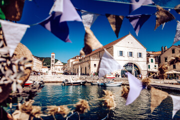 View of the boats bobbing gently in the harbor, framed by festive bunting and historic architecture under a clear blue sky, Hvar, Split-Dalmatia County, Croatia.