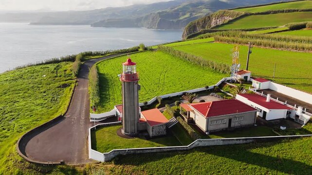 Aerial close view of Cintrao lighthouse in open green landscape on Sao Miguel Island, Azores