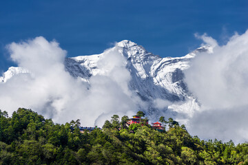 Tengboche monastery against high and snowy Kongde peak in sunny autumn day. View from the trail to Pangboche on Everest base camp trek, Nepal.