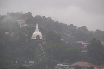 A view of the city of Kandy from the opposite shore of Lake Kandy, Sri Lanka. A historic Buddhist temple with a relic is located in this city. The rain begins during Hurricane Dilwa.