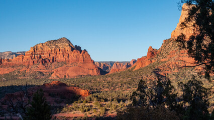 View of the sunlit red rock formations standing majestically against the azure sky, casting shadows across the desert landscape, Desert Hills, Arizona, United States.
