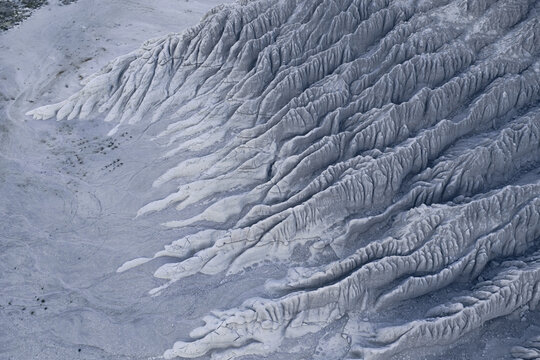 Aerial view of the alien landscape's stark, undulating ridges casting shadows, revealing a surreal, almost lunar terrain, Tuzbair, Mangystau Region, Kazakhstan.