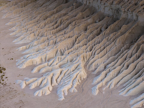 Aerial view of eroded sandstone formations create a surreal landscape of deep shadows and sunlit crests, Tuzbair, Mangystau Region, Kazakhstan.