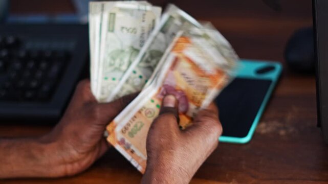 Man counting Indian currency notes for business or financial purpose, representing income and profit calculation.