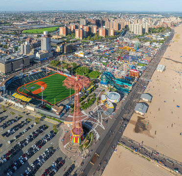 Aerial view of the vibrant Coney Island amusement park, its iconic Parachute Jump tower casting a shadow on the lively boardwalk, Brooklyn, New York, United States.