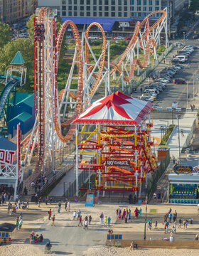 Aerial view of the Cyclone roller coaster and the red and white tent-like structure stand out amidst the bustling Coney Island, Brooklyn, New York, United States.