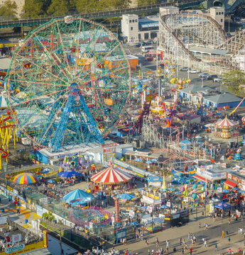 Aerial view of the vibrant and bustling Luna Park and Deno's Wonder Wheel Amusement Park, a kaleidoscope of colors against the backdrop of Coney Island, Brooklyn, New York, United States.