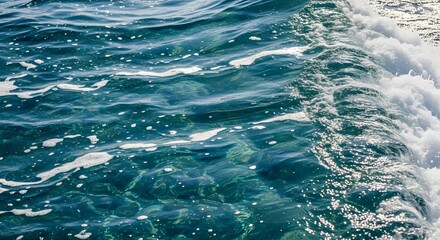 Turbulent ocean waves crashing against the shore with clear blue water and sunlight reflection