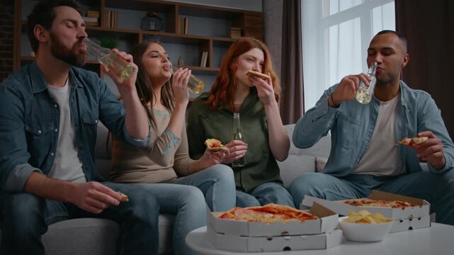 Happy diverse women men four friends with pizza beer dinking leisure rest at home party cooperation talking cheerful on couch food delivery multiracial friendly people gathering communicating dining