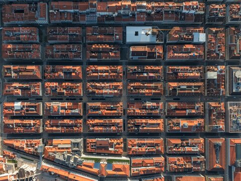 Aerial view of terracotta rooftops create a warm, patterned tapestry across the urban landscape, punctuated by linear streets and occasional modern structures, Lisbon, Lisbon, Portugal.