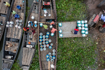 Sirajganj, Bangladesh - 12 July 2020: Aerial view of boats laden with containers, a symphony of blues and browns against the lush greenery, showcasing a vibrant riverine trade..