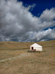 Yurt in Altai mountains under blue sky and clouds. Traditional dwelling of Turkic nomadic cattle breeders.