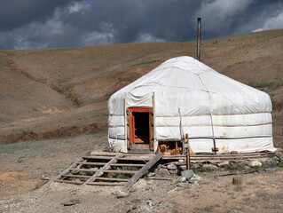 Yurt in Altai mountains under blue sky and clouds. Traditional dwelling of Turkic nomadic cattle breeders.