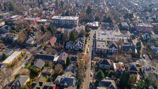 Aerial view of rooftops and tree canopies interspersed with buildings along Southeast 23rd Avenue, casting long shadows in the crisp morning light, Portland, Oregon, United States.