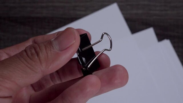 Hand Holding Binder Clip Securing Documents