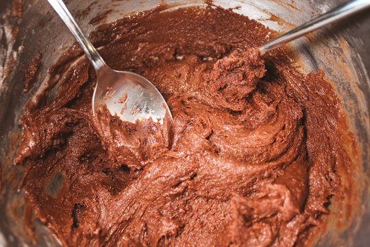 a bowl of chocolate cookie or pizzelle dough being mixed with spoons. baking background