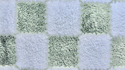 Fototapeta premium shaggy checkerboard rug texture in mint green and white fuzzy squares closeup for cozy home wallpaper or abstract design background
