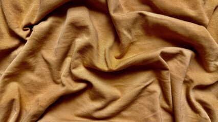 golden brown fabric texture wrinkles softly in closeup folds evoking warm luxurious depth for wallpaper or banner background