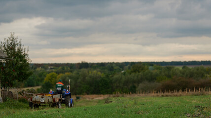 Fototapeta premium Farmer driving a tractor with a trailer through a field on a cloudy day