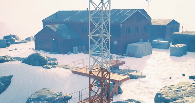 A communication tower stands tall in a snowy landscape, accompanied by several structures. The area is surrounded by rocky terrain and sparkling white snow, showcasing remote living conditions.