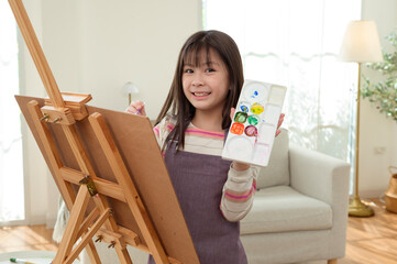 Child Creates Art While Standing at an Easel in a Bright Room During Daytime