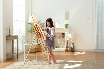 Child Creates Art While Standing at an Easel in a Bright Room During Daytime
