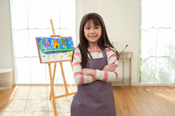 Child Creates Art While Standing at an Easel in a Bright Room During Daytime
