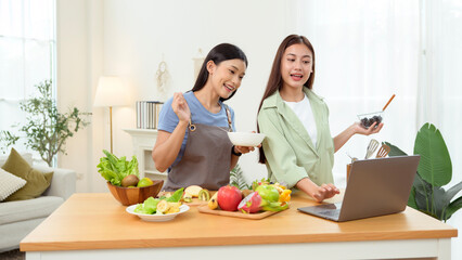 Friends Preparing a Healthy Meal Together in a Bright Kitchen While Using a Laptop for Recipes