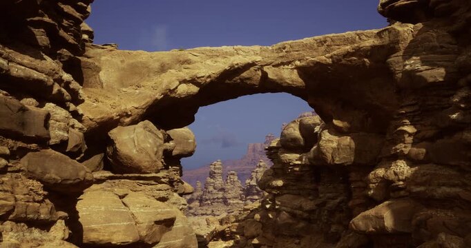 A breathtaking rock arch stands tall in a desert landscape, surrounded by unique geological formations of varying shapes and sizes under a clear blue sky in daylight.