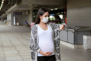 Pregnant woman wearing protective mask outdoors, health and maternity concept.