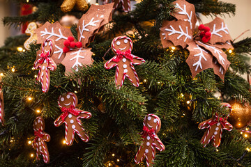 A Christmas tree decorated with gingerbread men and red bows on the city streets
