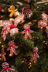 A Christmas tree decorated with gingerbread men and red bows on the city streets

