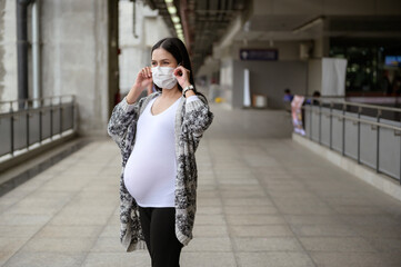 Pregnant woman wearing protective mask outdoors, health and maternity concept.