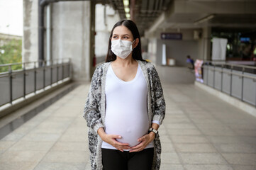 Pregnant woman wearing protective mask outdoors, health and maternity concept.