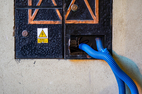 Electrical junction box in building facade with blue conduit urban technical infrastructure detail