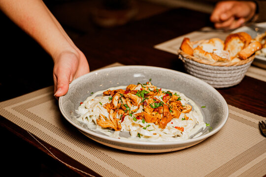 A waitress delivering a plate of pasta
