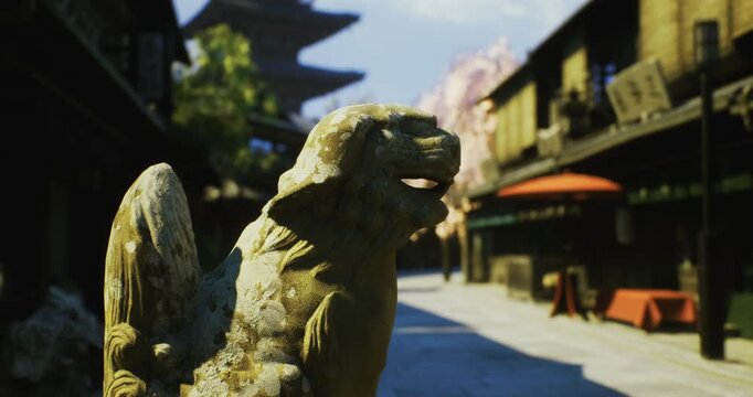 A weathered stone lion statue with wings watches over an old street lined with traditional buildings. Sunlight casts warm tones, enhancing the historic atmosphere of the location.