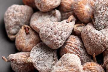 Dried figs covered with powdered sugar on a ceramic surface