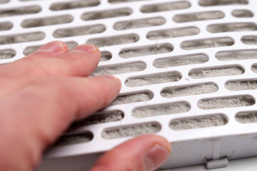 Air filter element clogged with dust fibers touched by a human hand. Used filtration cartridge