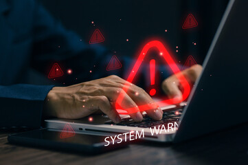 A red warning icon appears over a laptop as a professional types, representing system error alerts, cybersecurity threats, data breaches, risk detection, and IT problem management.