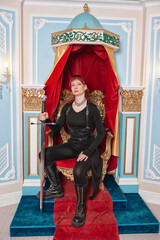 Beautiful redhaired woman warrior with sword sitting on the throne