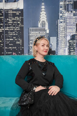 Beautiful blond woman sits on the sofa. Glamour style portrait