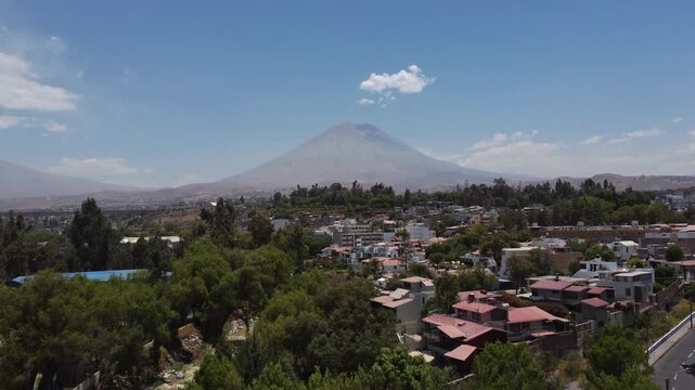 Aerial drone flying forward toward Misti Volcano with Arequipa city below, Peru