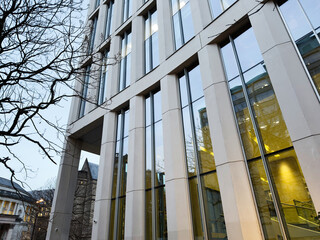 Naklejka premium Modern glass building in Manchester city center with bare trees and reflective windows