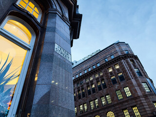 Historic stone building on Peter Street in Manchester with warm window light at dusk