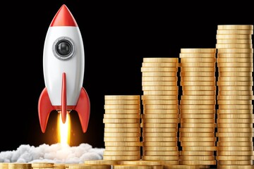 Rocket launching next to rising coin stacks showing business growth