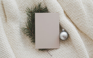 Mockup of vertical blank clean greeting card on knitted beige blanket, top view.
