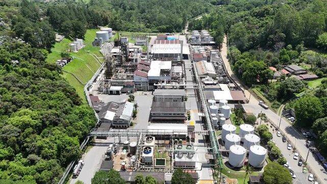 Vis&atilde;o a&eacute;rea de ind&uacute;stria petroqu&iacute;mica em funcionamento, com estruturas industriais, tanques e sistemas operacionais ativos, representando produ&ccedil;&atilde;o de energia, processos qu&iacute;micos