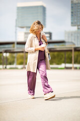 Stylish mature woman walking with coffee cup in urban area